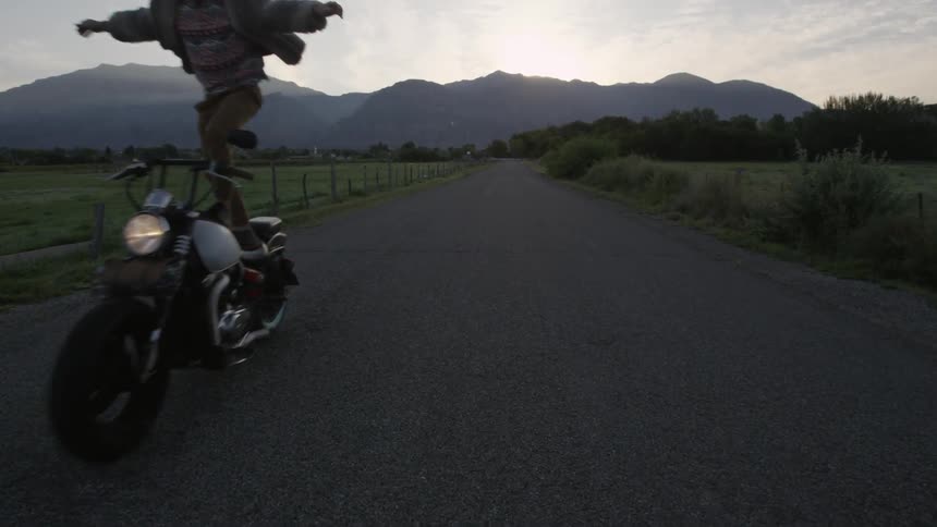Two men balance on motorcycles in a rural area