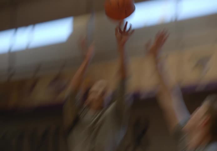 Two men playing on a basketball court and one of them scoring a field goal