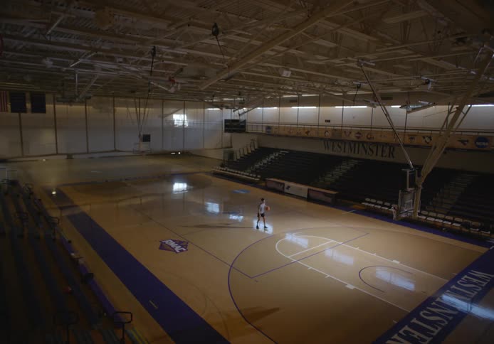 Man practicing basketball and successfully scoring on an empty university basketball court
