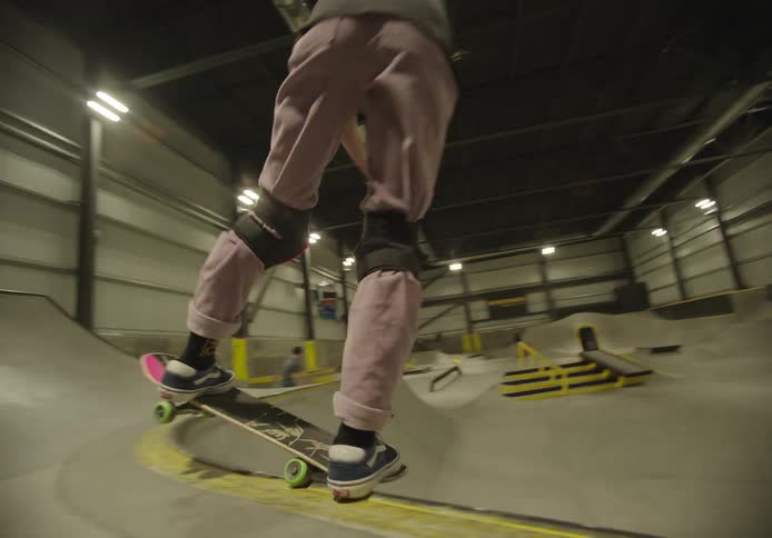 Teenager girl wearing a helmet skateboarding on a ramp indoors