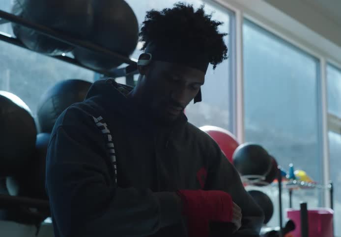 A man wraps his hands in hand wraps while sitting in a gym
