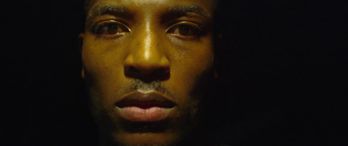 Face of a black man indoors going from shadow to light at intervals