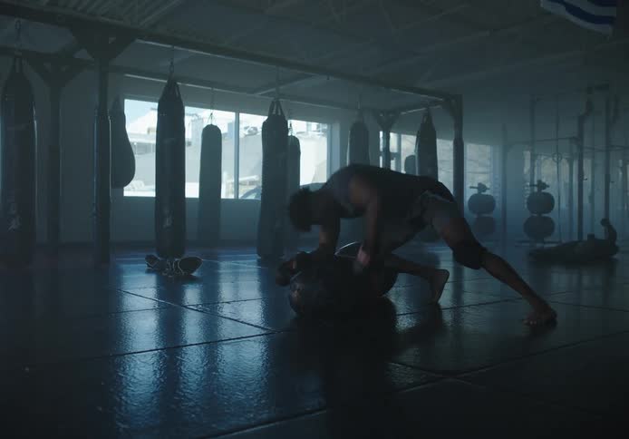 Man training boxing in an empty gym aggressively punching the boxing bag on the floor