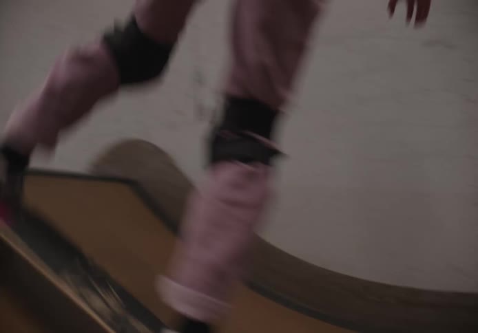 A girl is skating on the ramp inside