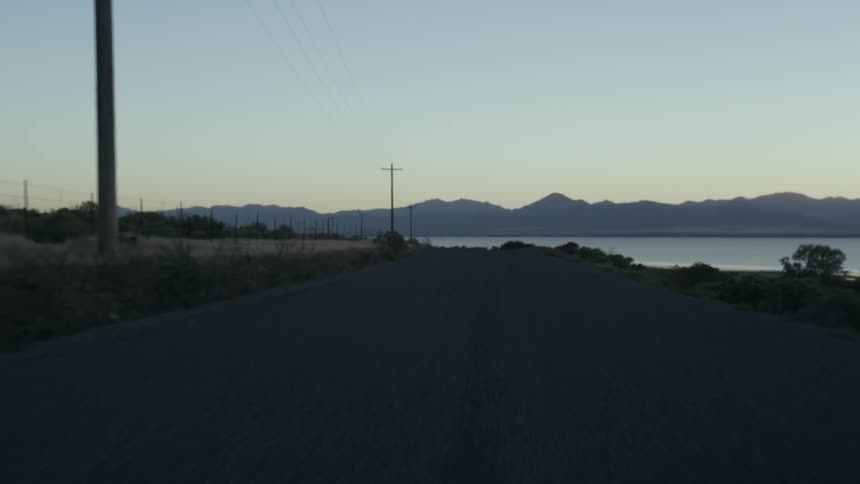 Moving down a small road by the water at sunset