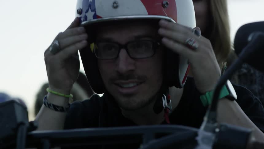A man puts his helmet on sitting on a motorcycle with a woman