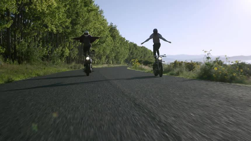 Two people ride motorcycles standing up