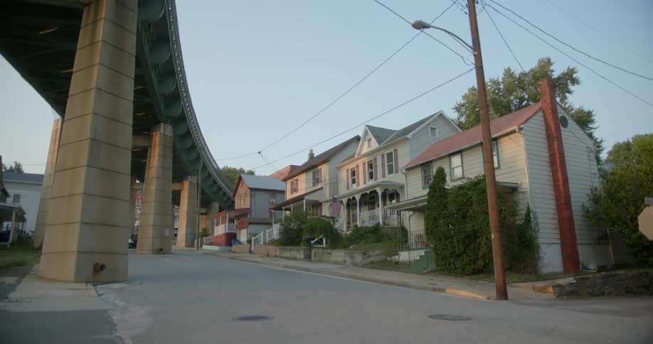 A row of residential homes stand beneath a tall overpass