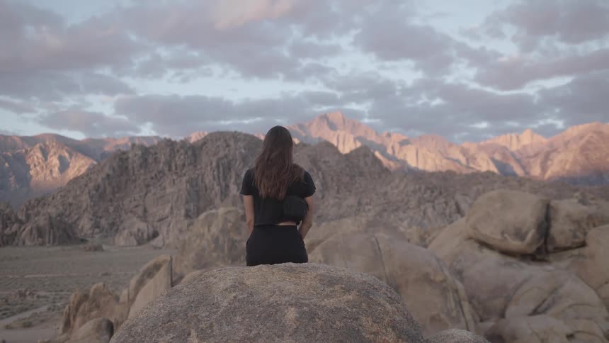 A woman is sitting on a boulder