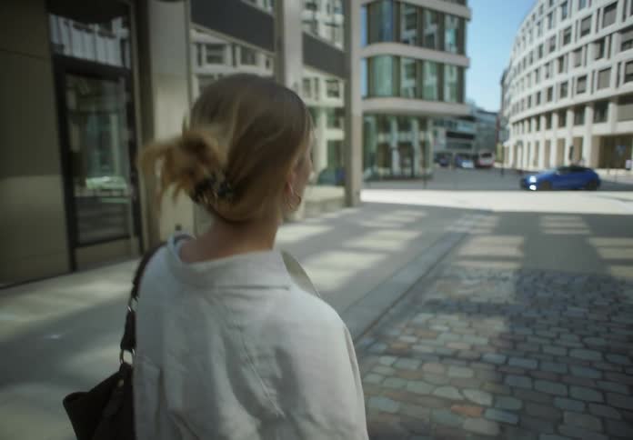 A woman walking through a city while on a call turns around