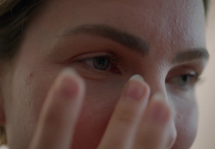 A woman gently massaging cream onto her face