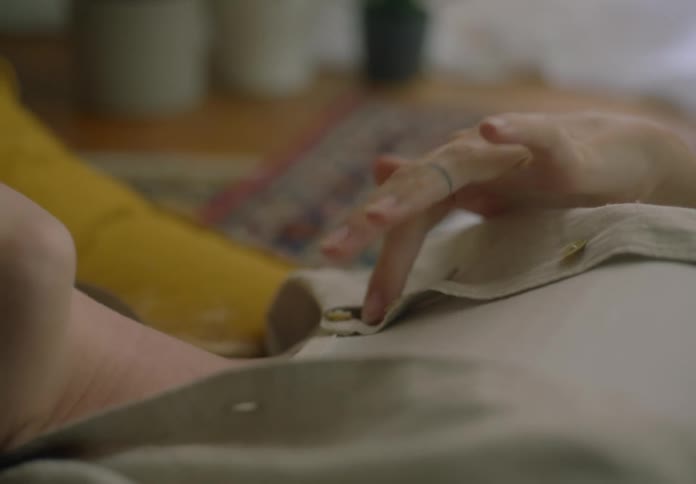 A woman is laying on the floor at home, fiddeling with her shirt