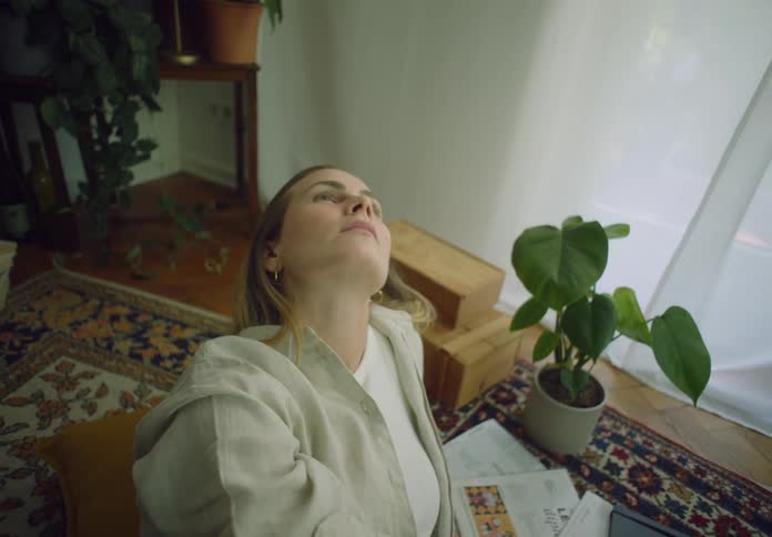 Blonde woman lying down on a rug touching her hair
