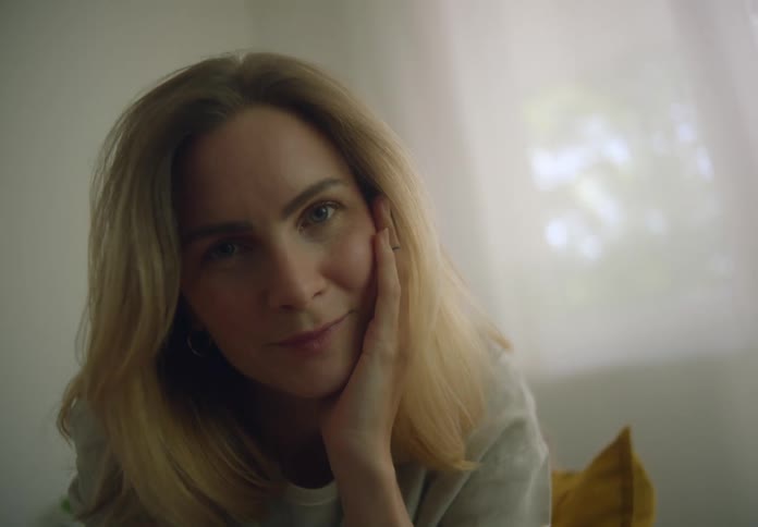 Blonde woman inside the house gently caressing her face