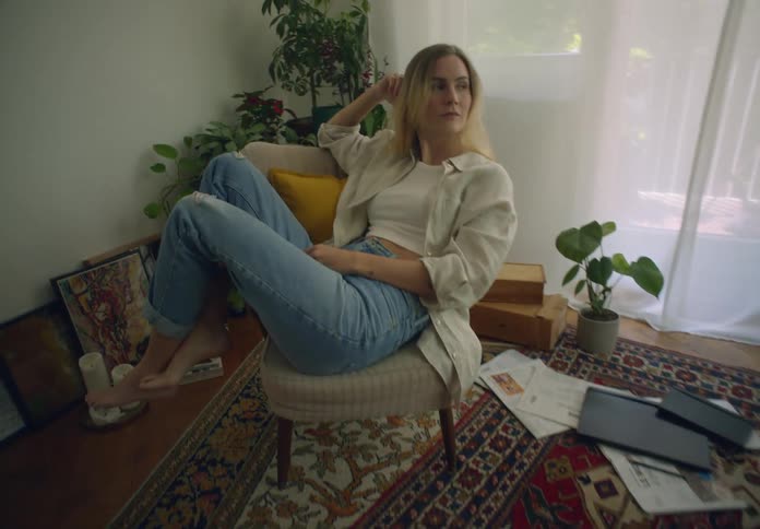 Blonde woman sitting on a chair touching the back of her head