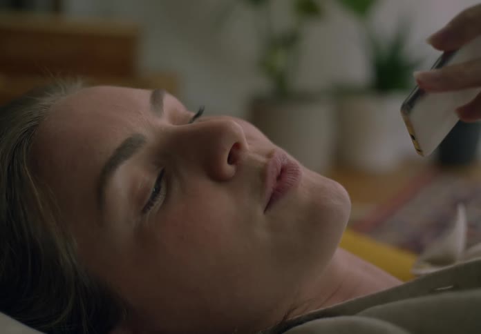 Woman lying on a cushion on the living room floor talking on the phone