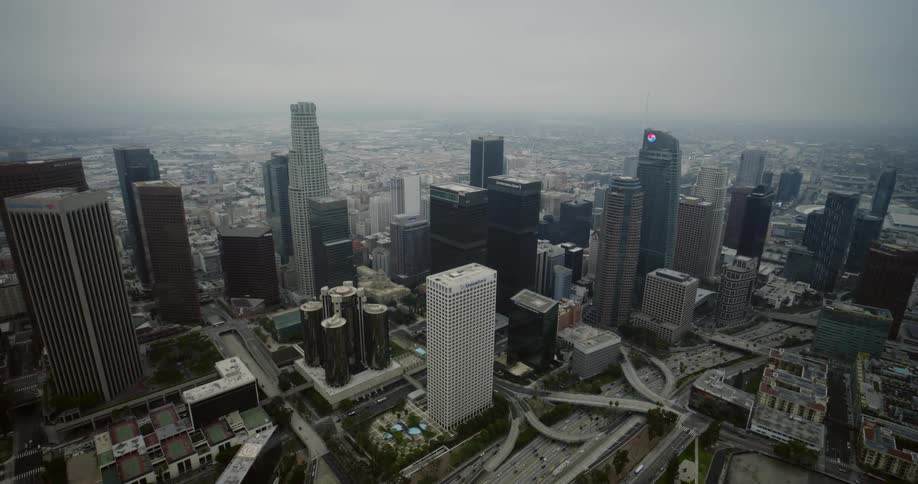 Skyscrapers loom over a freeway in a metropolis on a foggy day