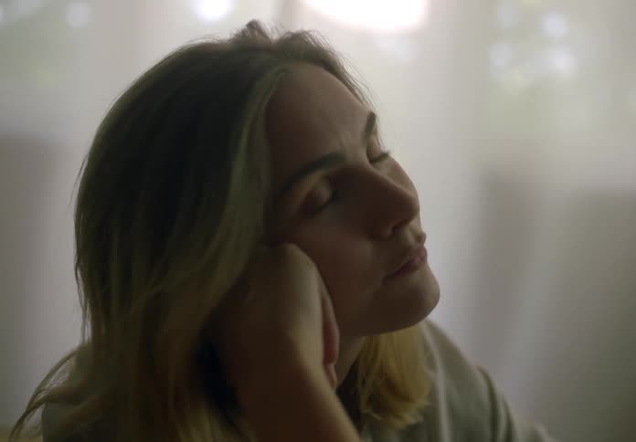 Blonde woman with an introspective and thoughtful expression inside her house