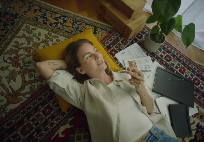 A woman is laying down on the floor talking on her phone
