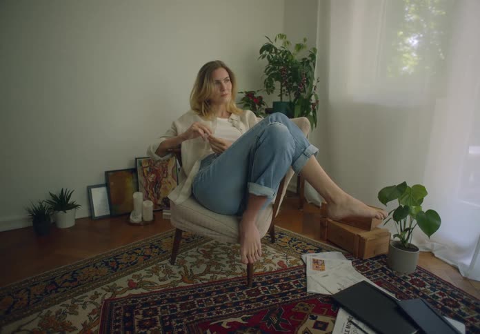A woman is lounging on a chair next to a window