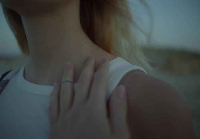 Blonde woman outdoors caressing her neck