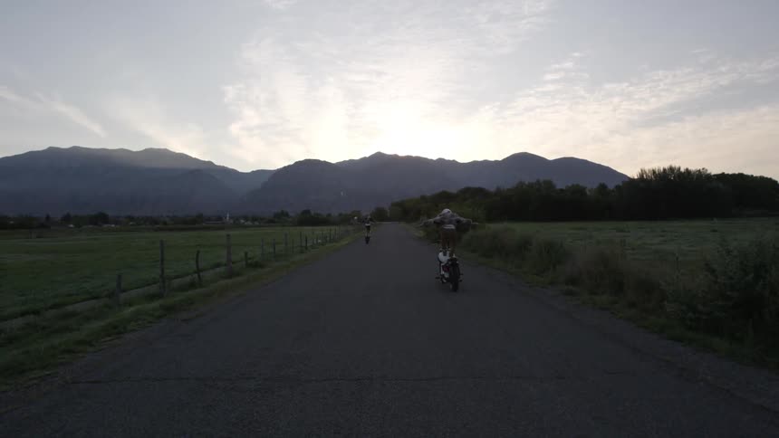 A person is standing on a motorcycle as they ride down the road