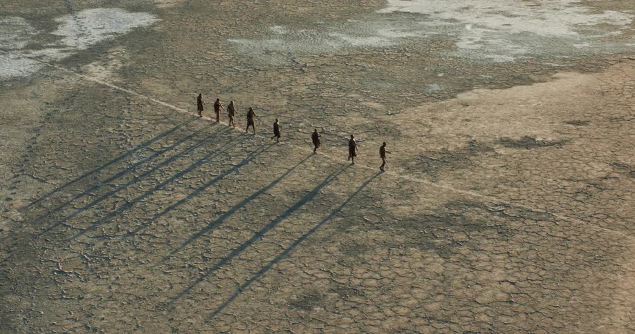 Row of bushmen walking on a path in the middle of the salt pan
