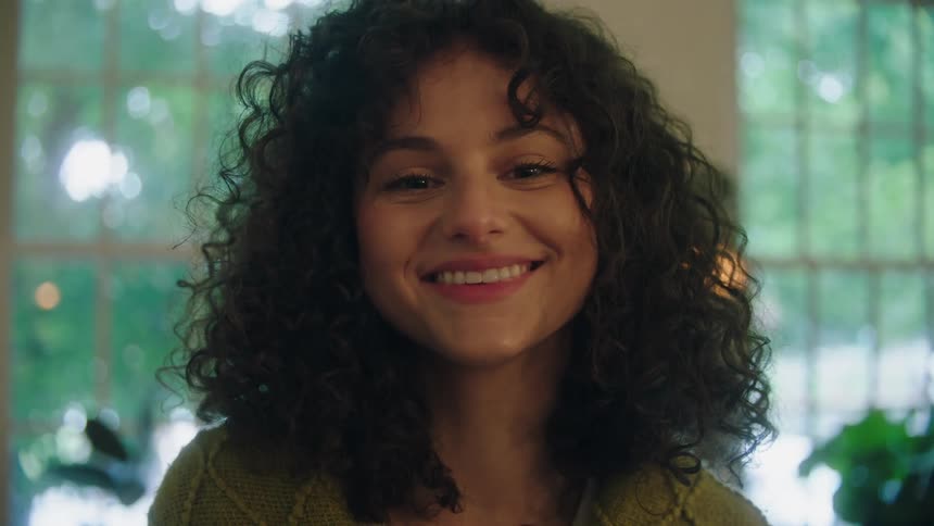 Young woman with curly hair smiling indoors