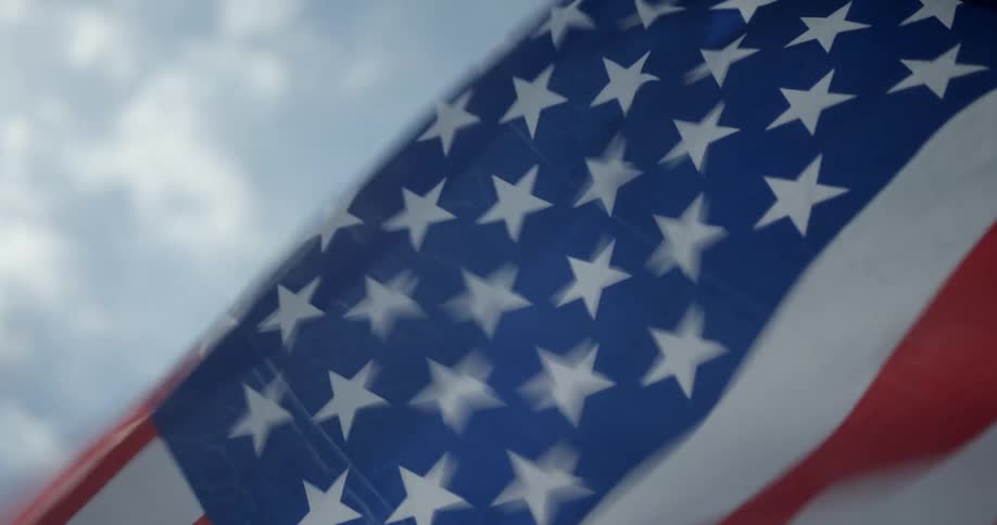 An american flag flaps very rapidly as it is blown by very fast wind