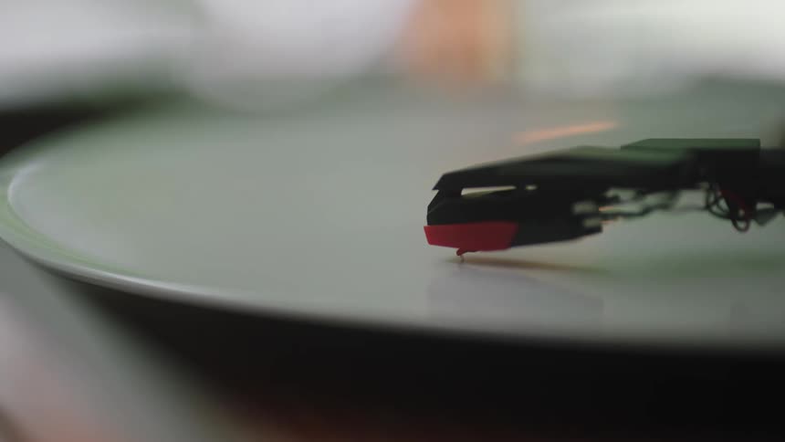 A stylus of a record player descends to touch the surface of a record