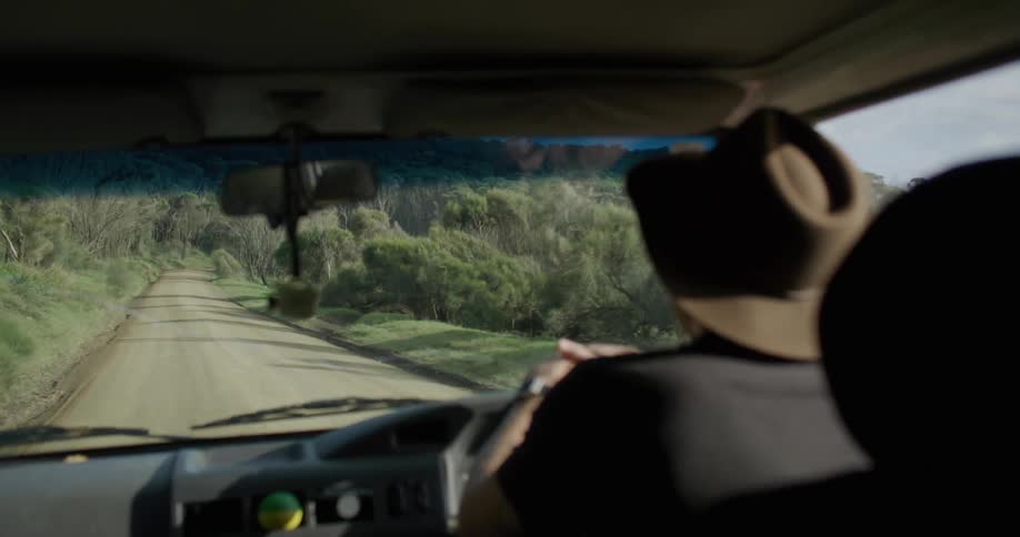 A man driving a vehicle on a dirt road surrounded by vegetation