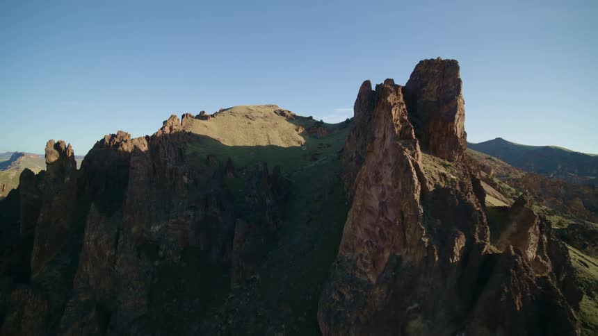 Pinnacles and a narrow rock cliff stand tall against the sun