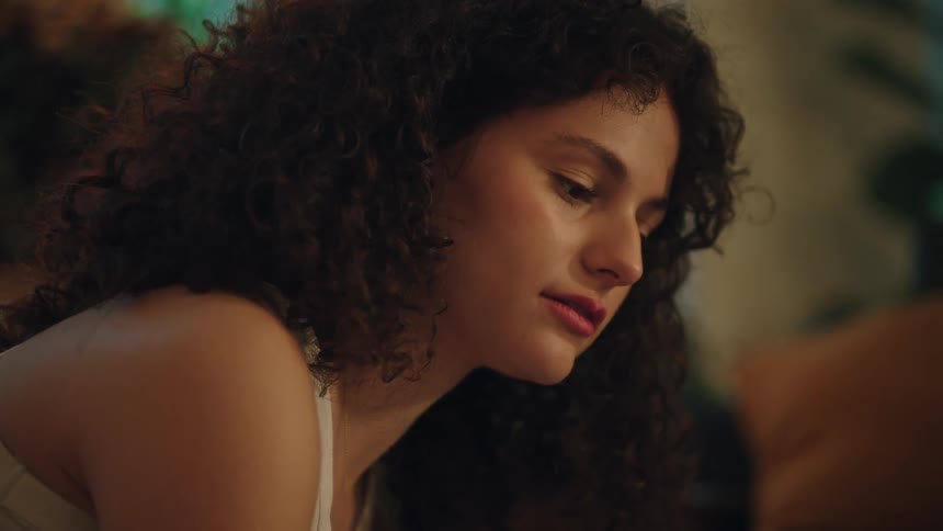 A young woman with curly hair contemplates how to decorate the room