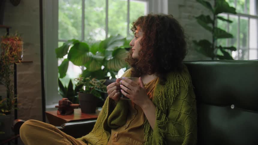 Girl sitting on a couch holding a cup of coffee