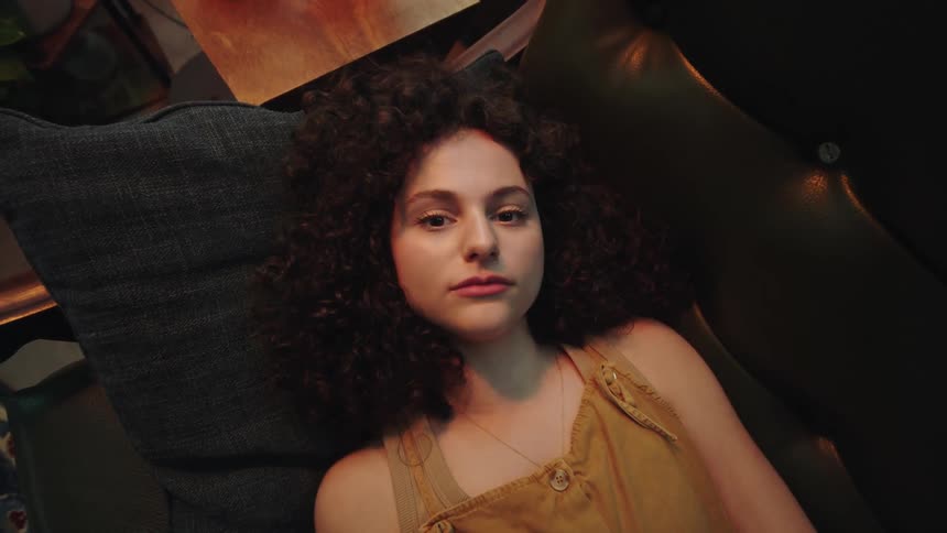 Darkhaired woman lying down on a couch posing with different face expressions and angles