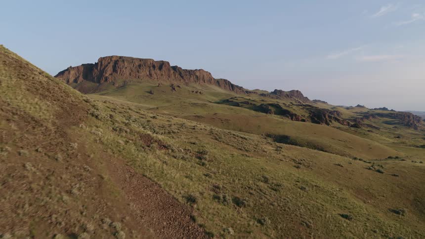 Reveal of rugged and mountainous countryside from behind a sage dotted rocky ridge