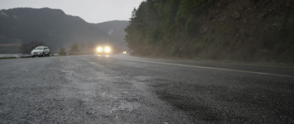 Big rig tractor pulling construction equipment passes on a mountain road
