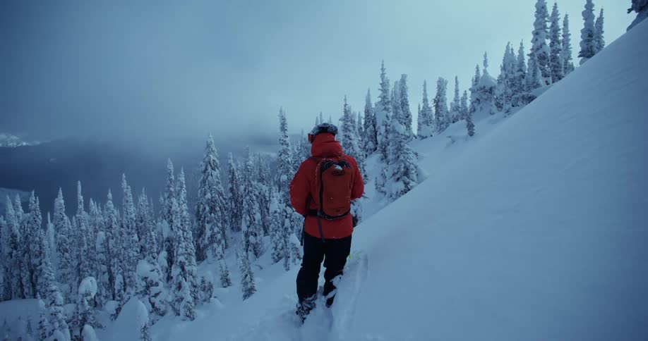 A person is hiking on the side of a mountain landscape in winter