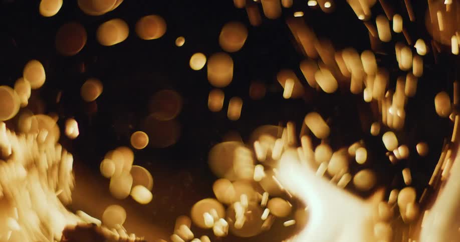 Sparks rise floating from a campfire at night