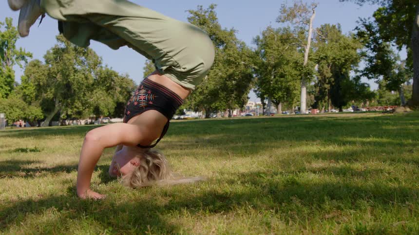 A woman is doing stretches outdoors in the grass