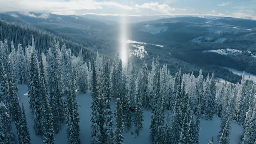 A snow plow drives through a snow covered forest in the mountains