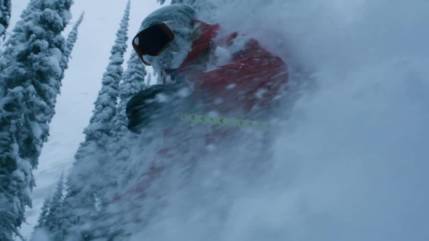 A person skis downhill through deep snow at a very fast pace