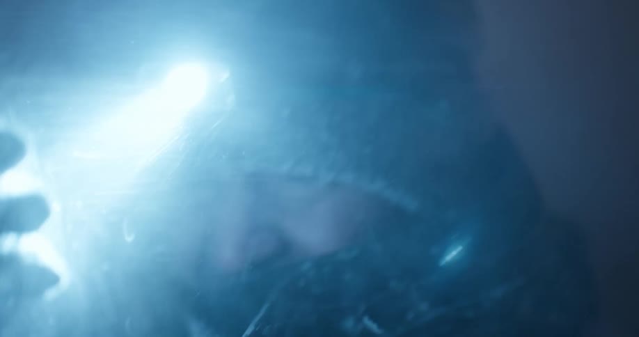 A man with a headlamp on at night shields his face from the blowing snow