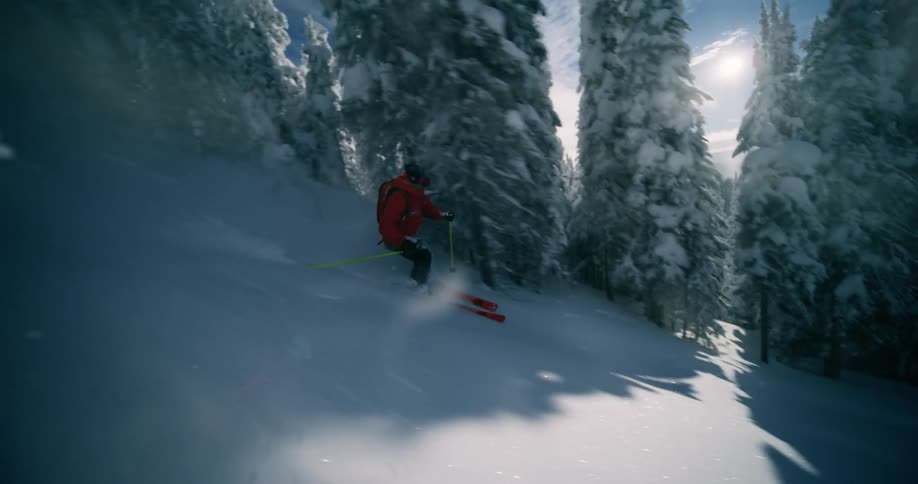 A person is skiing down a snow covered mountain during midday