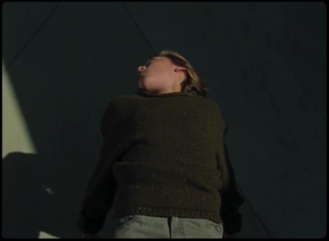 Woman stands with her head to the side as moving structure castsshadow