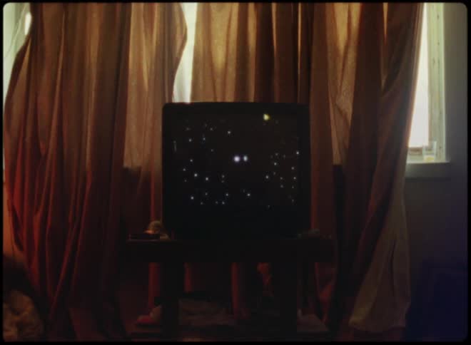 An old television on a stand in a room in front of curtains blocking daylight