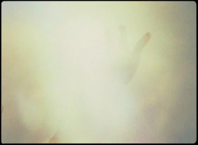 A person holds their hands upwards towards the sky as the sun shines brightly