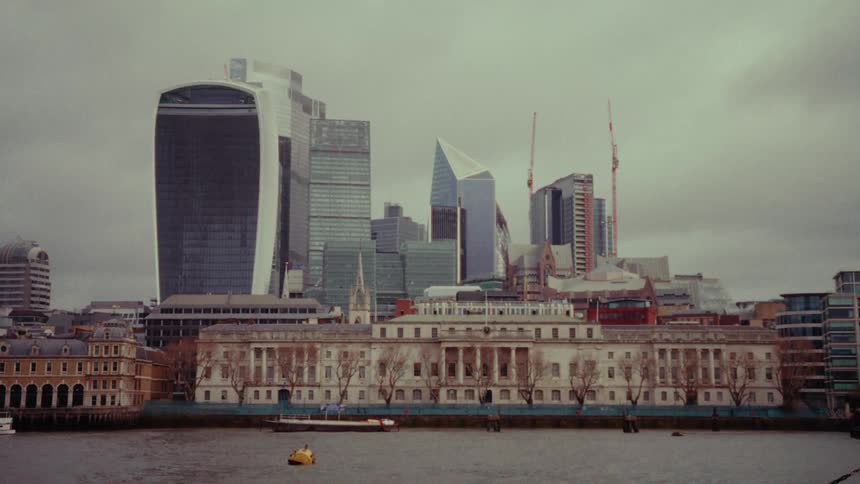 Skyscrapers in a city near a river with boats on a cloudy day