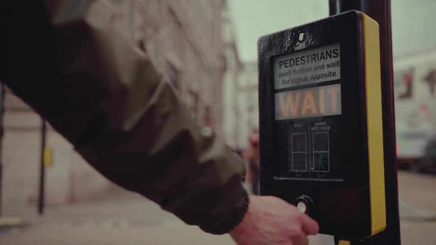 A person presses the button to cross the street