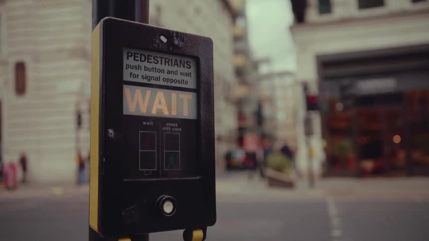 Man pushes button on crosswalk control near busy downtown intersection